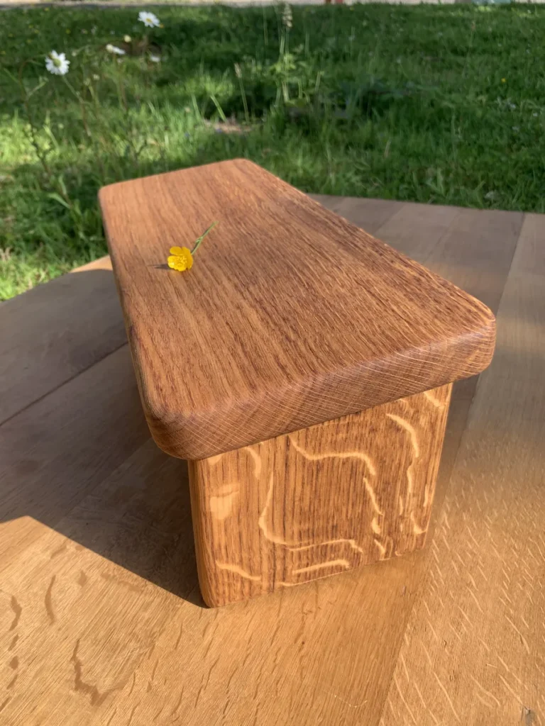 Banc de méditation eco-responsable en chêne rouge massif, vue de profil, magnifique maillage apparent, dans la chaude lumière naturelle.